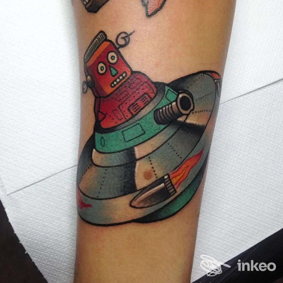 Tatuaggio colorato su avambraccio raffigurante un robot in un disco volante. Lavoro mostrato da Veracruz Tattoo Torino, Torino.