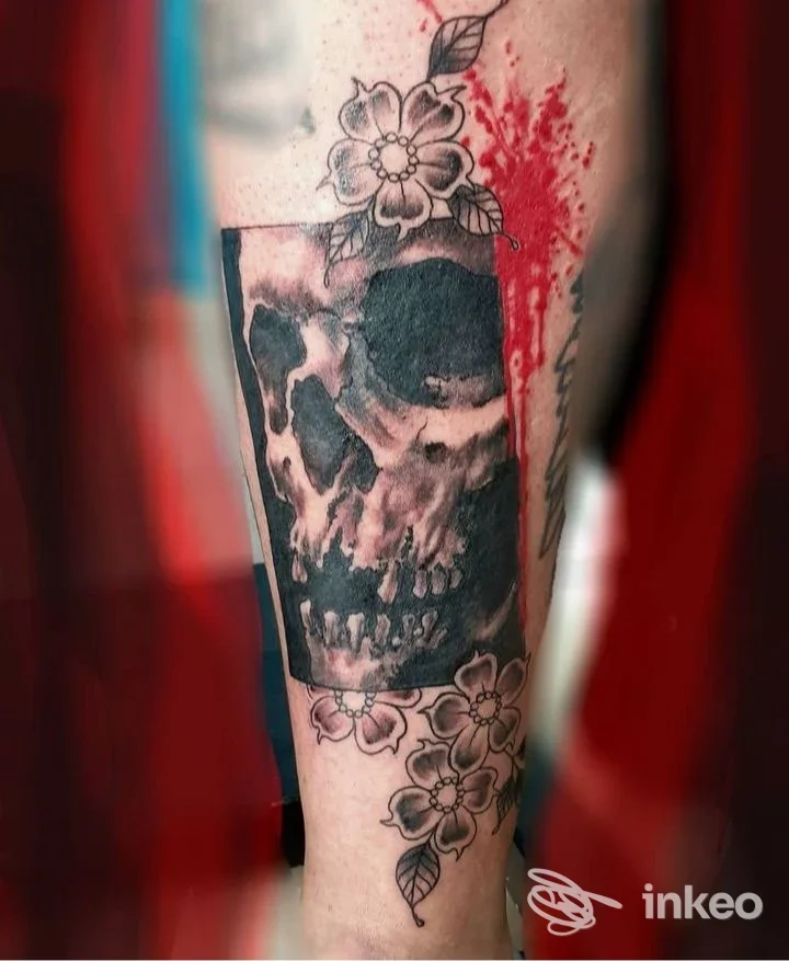 Tatuaggio teschio con fiori e schizzi rossi sull'avambraccio, lavoro di art tattoo di roberto mossino a Chiusa di San Michele.