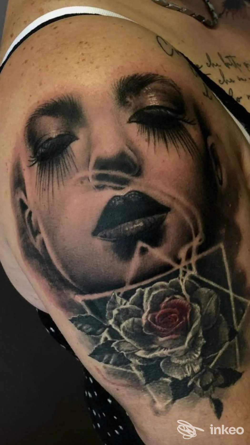 Tatuaggio realistico di un volto femminile in bianco e nero con una rosa colorata sotto, visibile sulla spalla: Alo Ink Tattoo Studio, Leini.