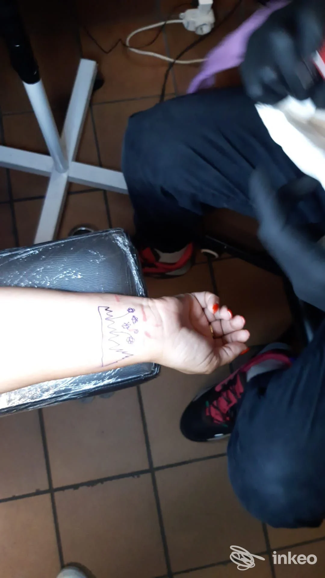 Primo piano del polso con disegno preparatorio per tatuaggio; operatore con guanto nero in studio Born To Bleed Tattoo Shop, Novara.