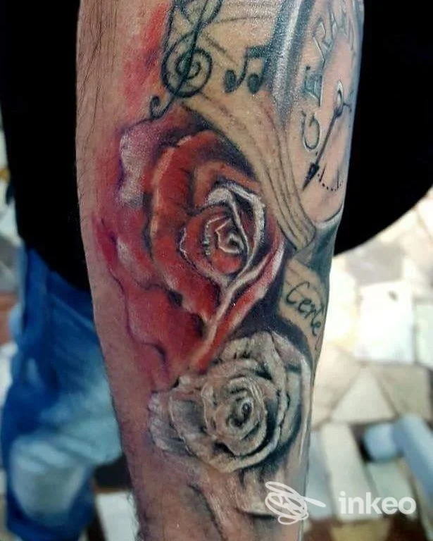Primo piano di tatuaggio con rose e note musicali sull'avambraccio. Creation Tattoo di Marini Gualtiero, Torino.