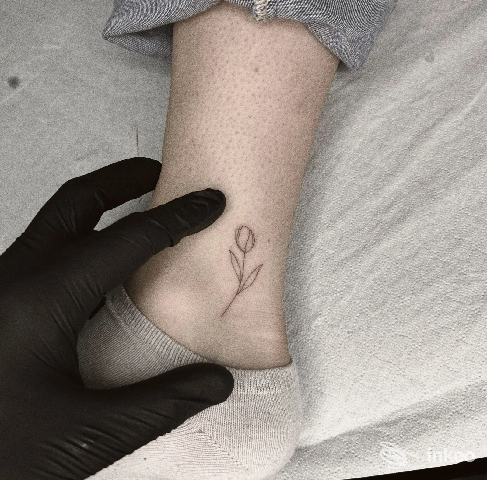 Primo piano di un piccolo tatuaggio a forma di tulipano sulla caviglia, foto scattata in studio Blackout Tattoo Studio, Torino.