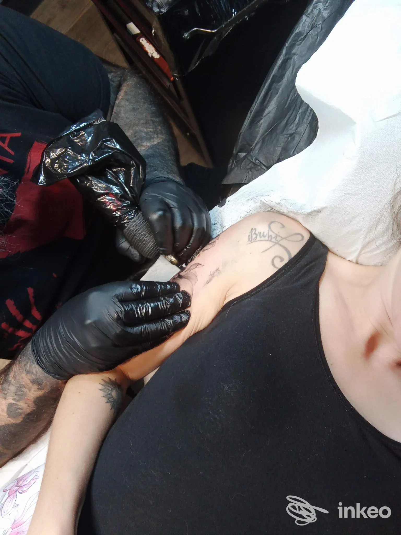 Tatuaggio in corso sulla parte interna del braccio superiore, operatore con guanti neri. Deep Line Tattoo, Cuneo.
