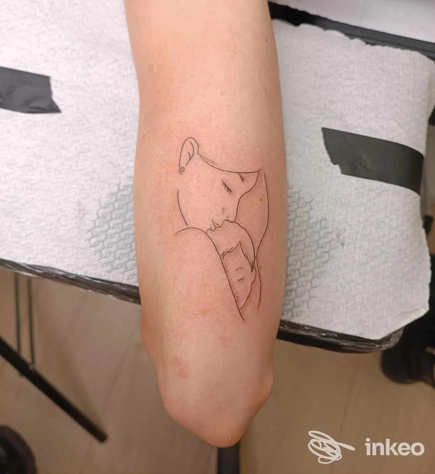Tattoo a linea sottile su avambraccio raffigurante un gatto che dorme, realizzazione corporea visibile su pelle, disegno minimale su sfondo neutro; studio Crilly Ink Tattoo Studio.