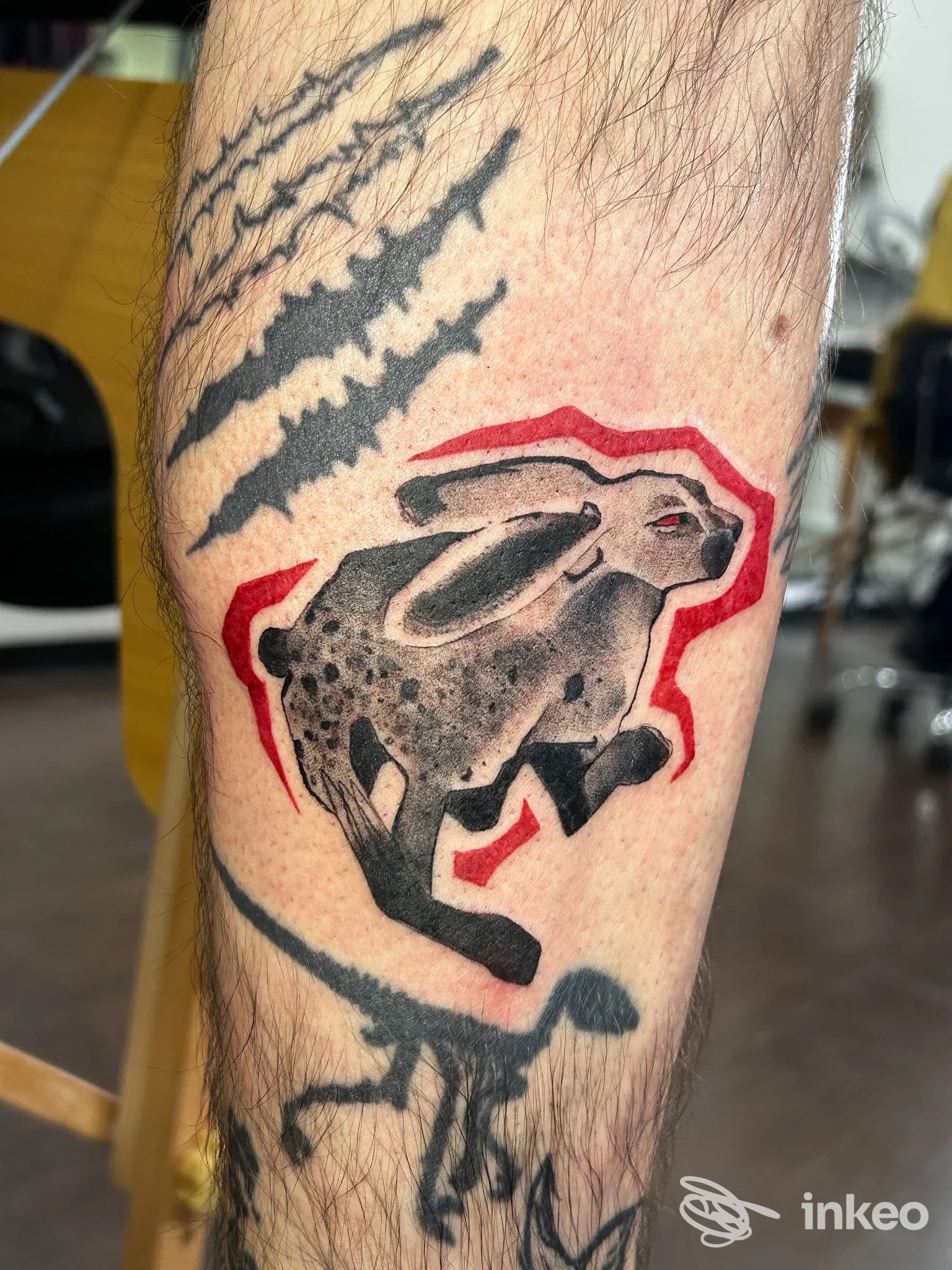 Tatuaggio di un coniglio stilizzato in nero con contorno rosso sull'avambraccio, Inker's Club Coworking Tattoo Studio, Torino.