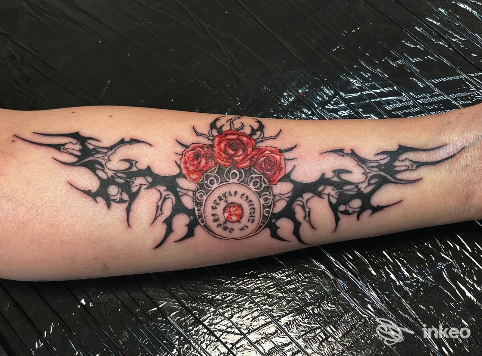 Tatuaggio con elementi tribali neri e tre rose rosse sull'avambraccio, realizzato da Insomnia Tattoo Studio a Omegna.