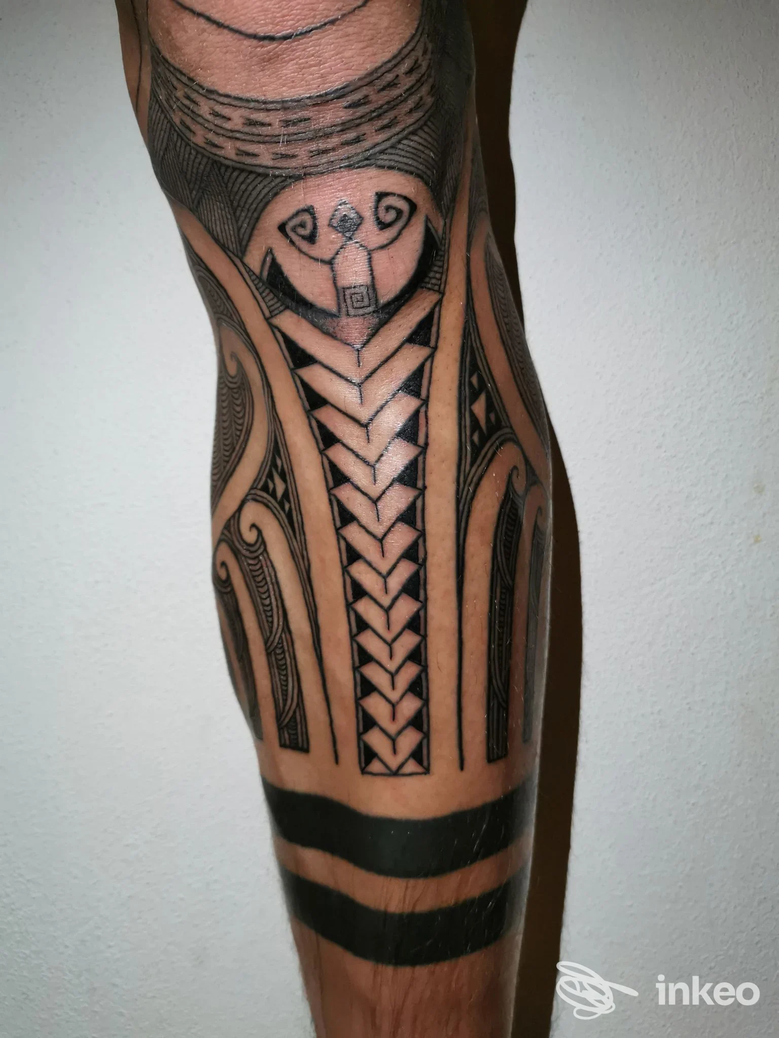 Tattoo visibile su polpaccio con motivo geometrico in nero, linee ad intreccio e ornamenti decorativi visibili sulla pelle.