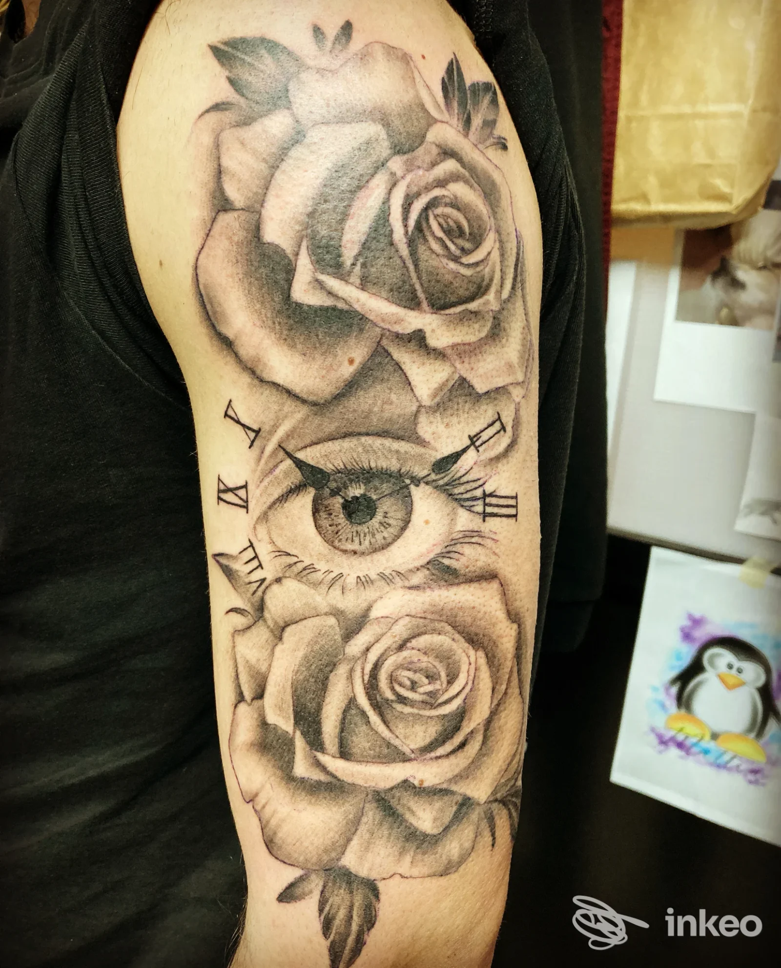 Tatuaggio black&grey su braccio superiore con rose e un occhio, foto fornita da Eikon Tattoo Studio, Novara.