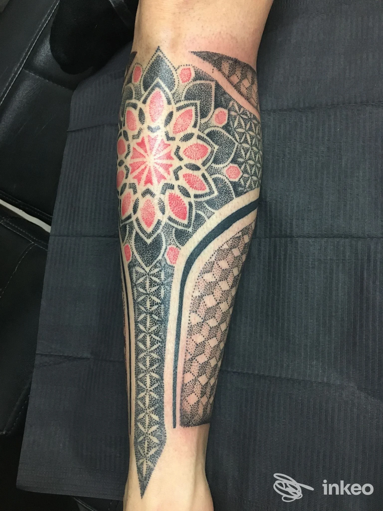 Avambraccio tatuato con motivi geometrici e mandala in nero e rosso, foto per Eikon Tattoo Studio, Novara.