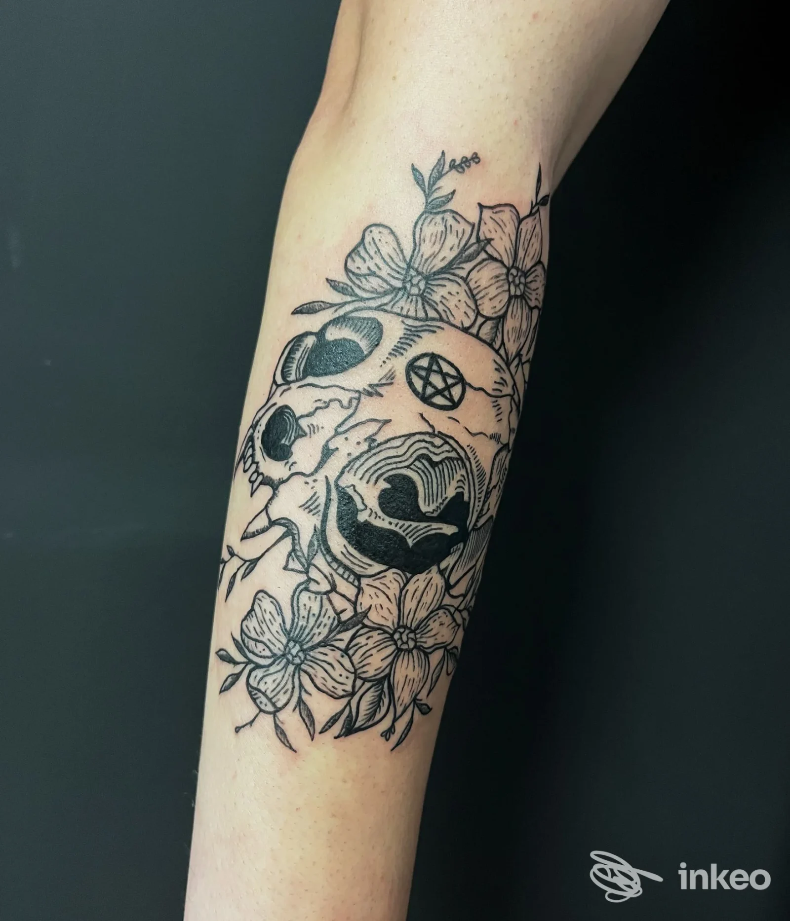 Tatuaggio in bianco e nero sull'avambraccio con teschio stilizzato e fiori, fotografia fornita da LaBlu Tattoo Studio, Torino.