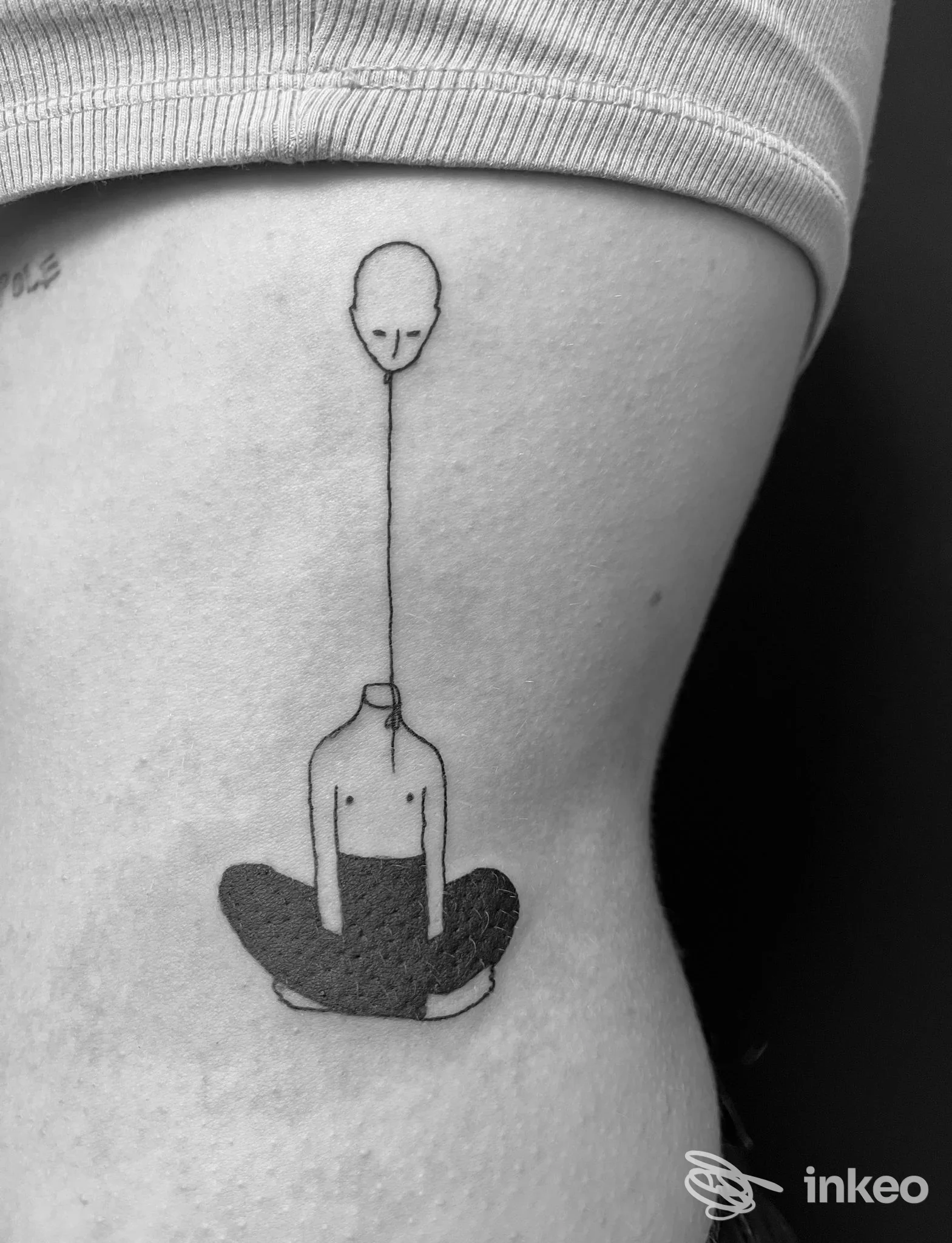 Tatuaggio minimal a linee nere sul fianco: figura stilizzata seduta con testa collegata da una linea sottile. LaBlu Tattoo Studio, Torino.