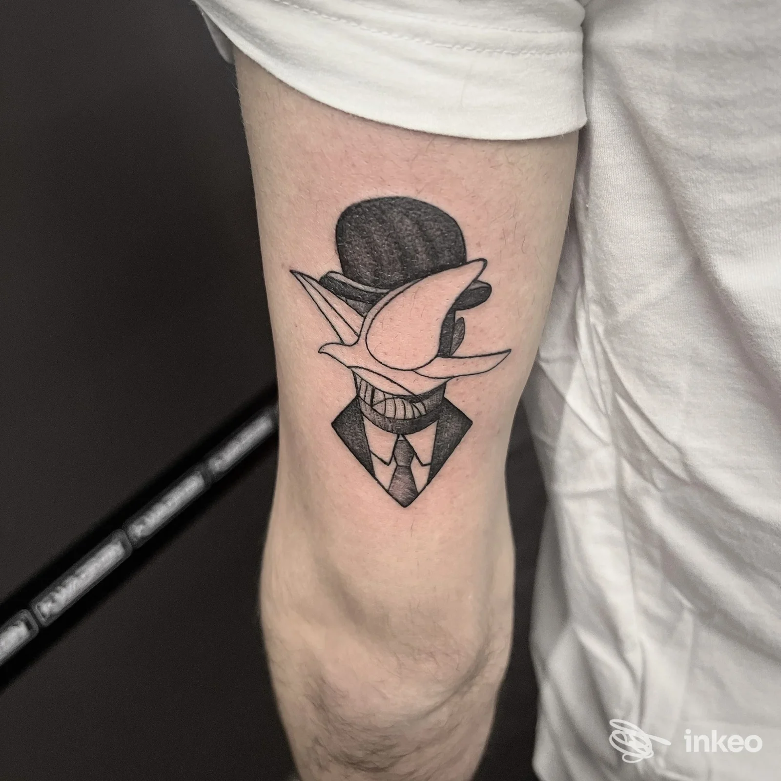 Tatuaggio stilizzato su avambraccio realizzato da Inkubus Tattoo Piercing a Rivarolo Canavese, figura con bombetta e sorriso.