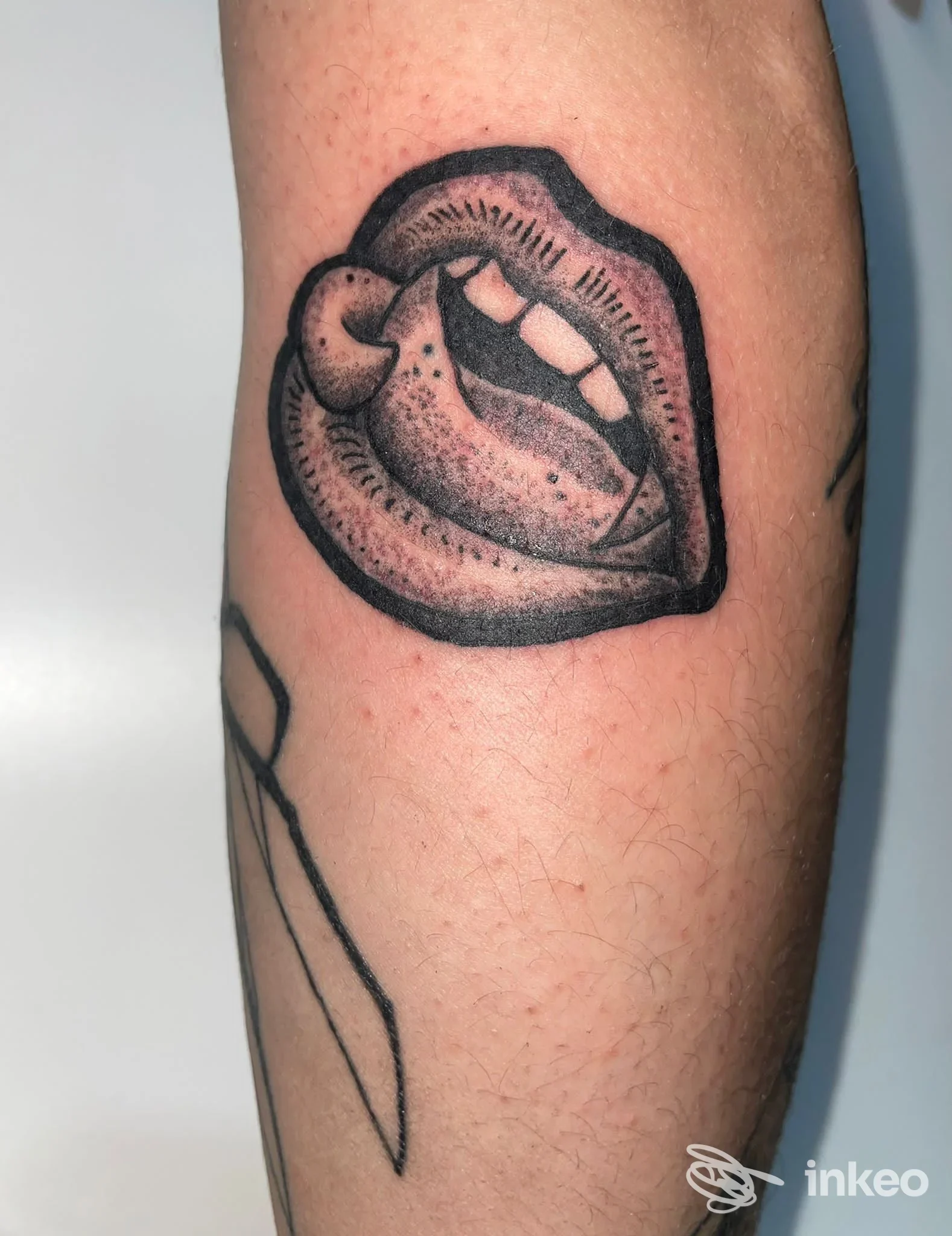 Primo piano di un tatuaggio stilizzato di labbra con lingua su avambraccio, realizzato da Magic tattoo vintage a Carignano su pelle reale.