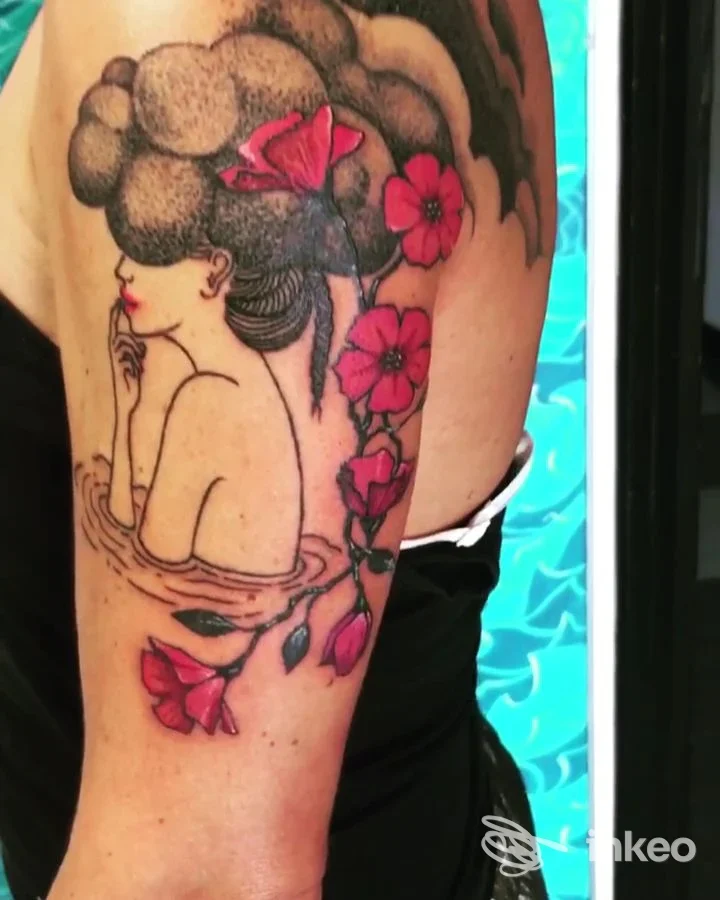 Tatuaggio colorato di una donna stilizzata con fiori sul braccio superiore, fotografato per Mauri's Tattoo & Gallery a Borgomanero.