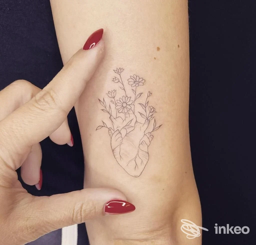 Fotografia del polso con piccolo tatuaggio linee sottili a cuore anatomico e fiori, Oonà TATTOO, Torino.