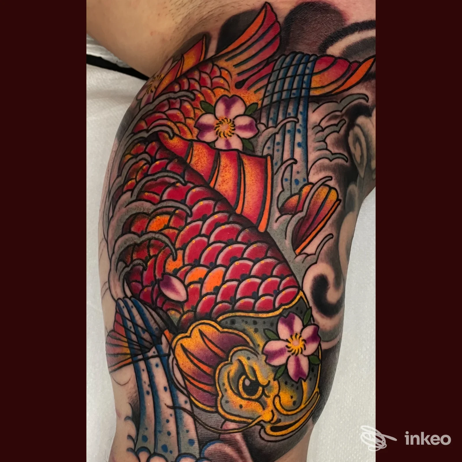 Tatuaggio colorato a tema carpa sul braccio superiore, foto da SIMOHOLY quality Tattoo&Piercing a Viverone.
