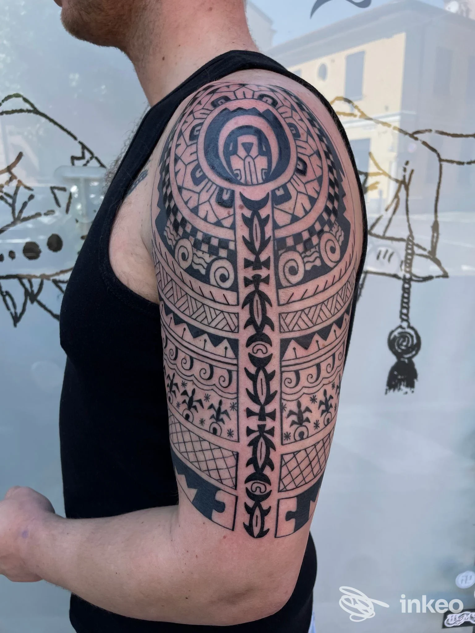 Tattoo geometrico-tribale a manica sull’avambraccio di un uomo, tratto in primo piano con colori neri su pelle visibile, senza testo né interfacce sociali visibili.