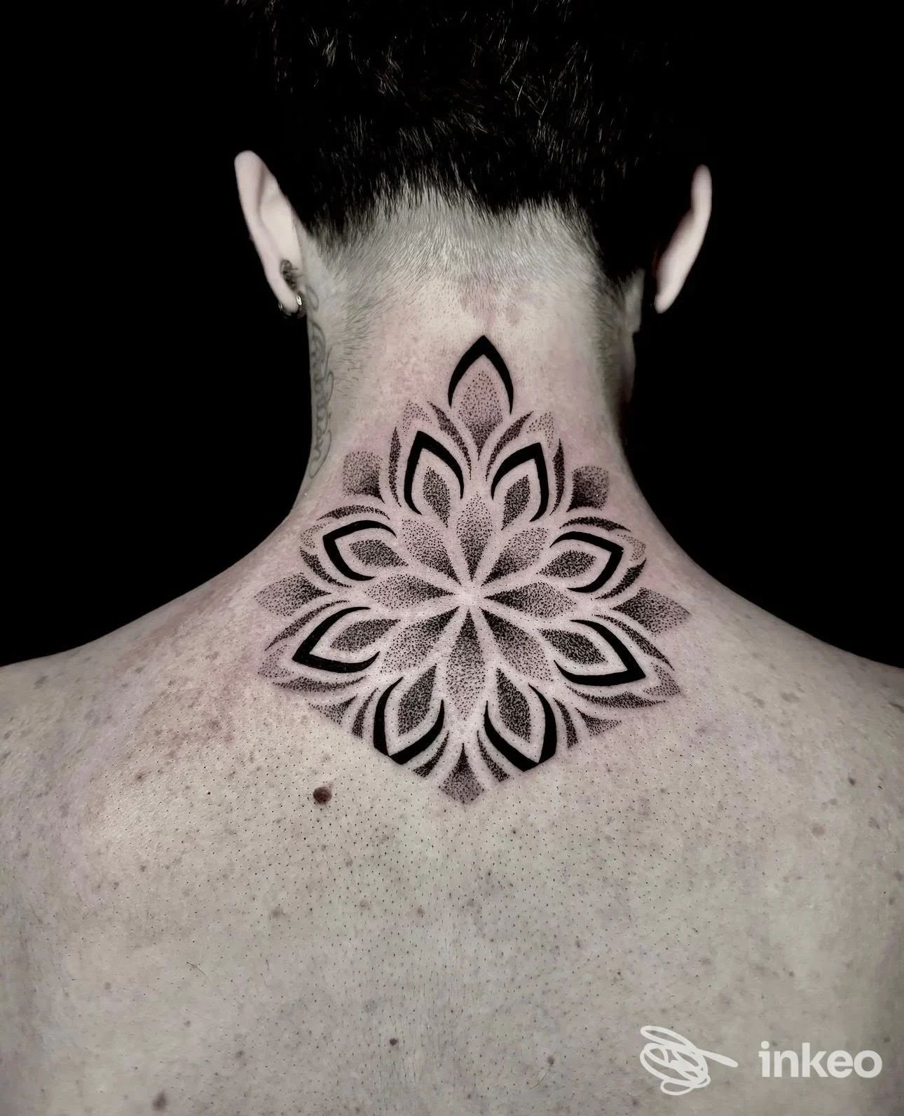 Grande tatuaggio ornamentale nero al centro della nuca e parte superiore della schiena, foto inviata da Reborn Tattoo Studio, Torino.