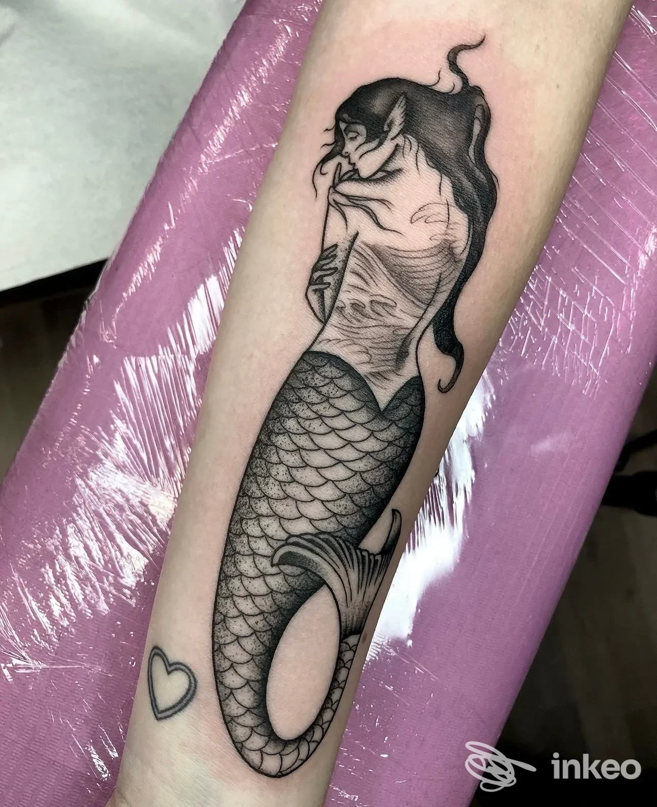 Tatuaggio nero-grigio di una sirena sull'avambraccio, realizzato da Reborn Tattoo Studio a Torino, con piccolo cuore vicino al polso.