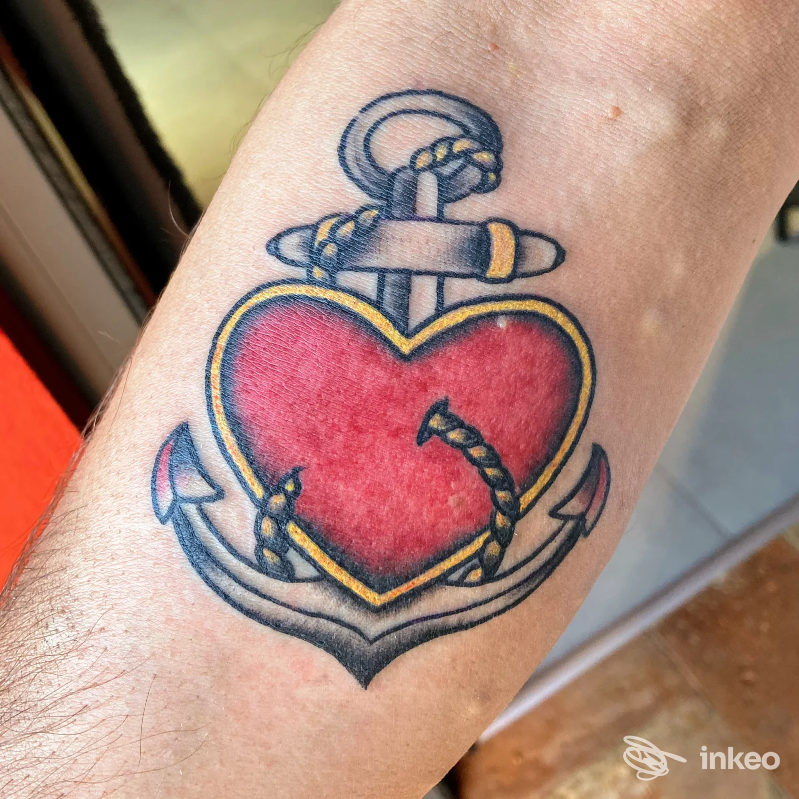 Tatuaggio tradizionale su avambraccio: ancora con cuore rosso e corda, foto da Redrum Tattoo, Carpignano Sesia.