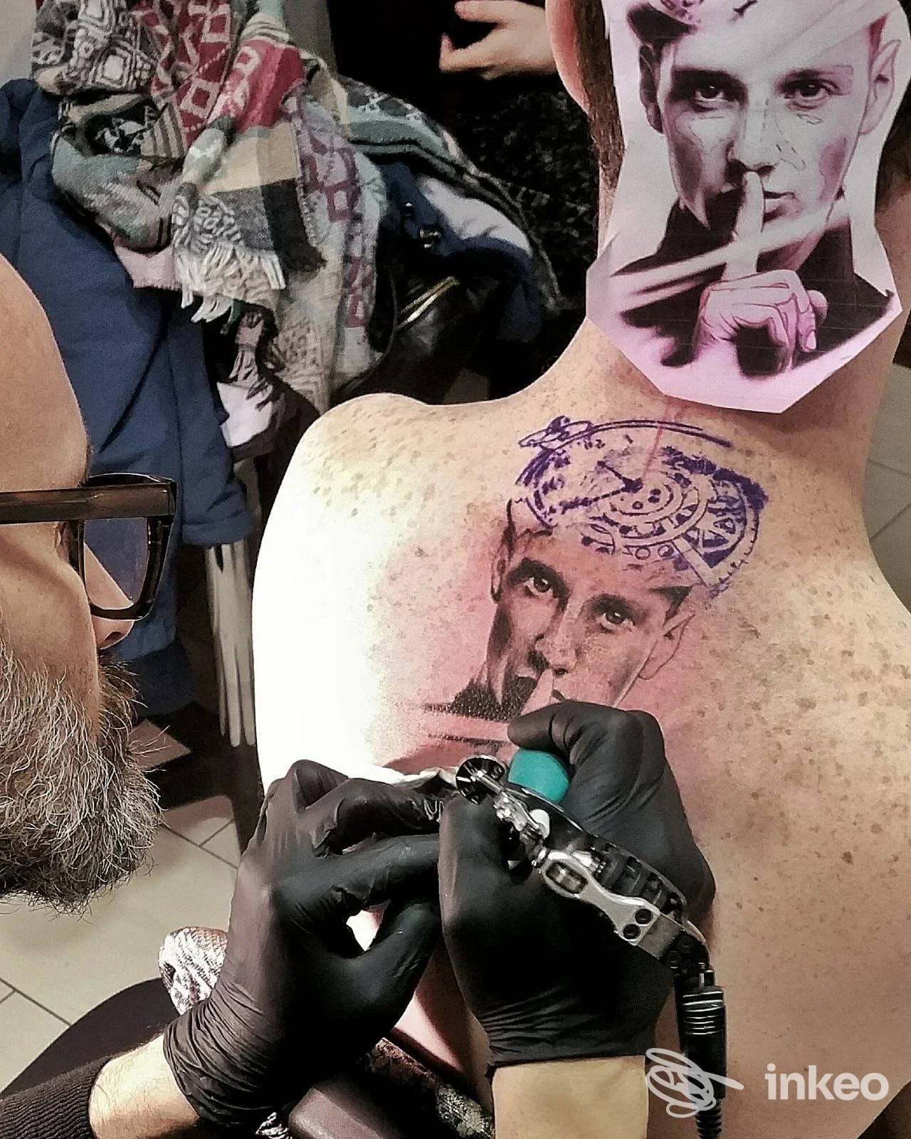 Tatuaggio su dorso e nuca in corso presso Studio Sottopelle Tatoo e Piercing a Savigliano, tatuatore al lavoro con macchinetta.
