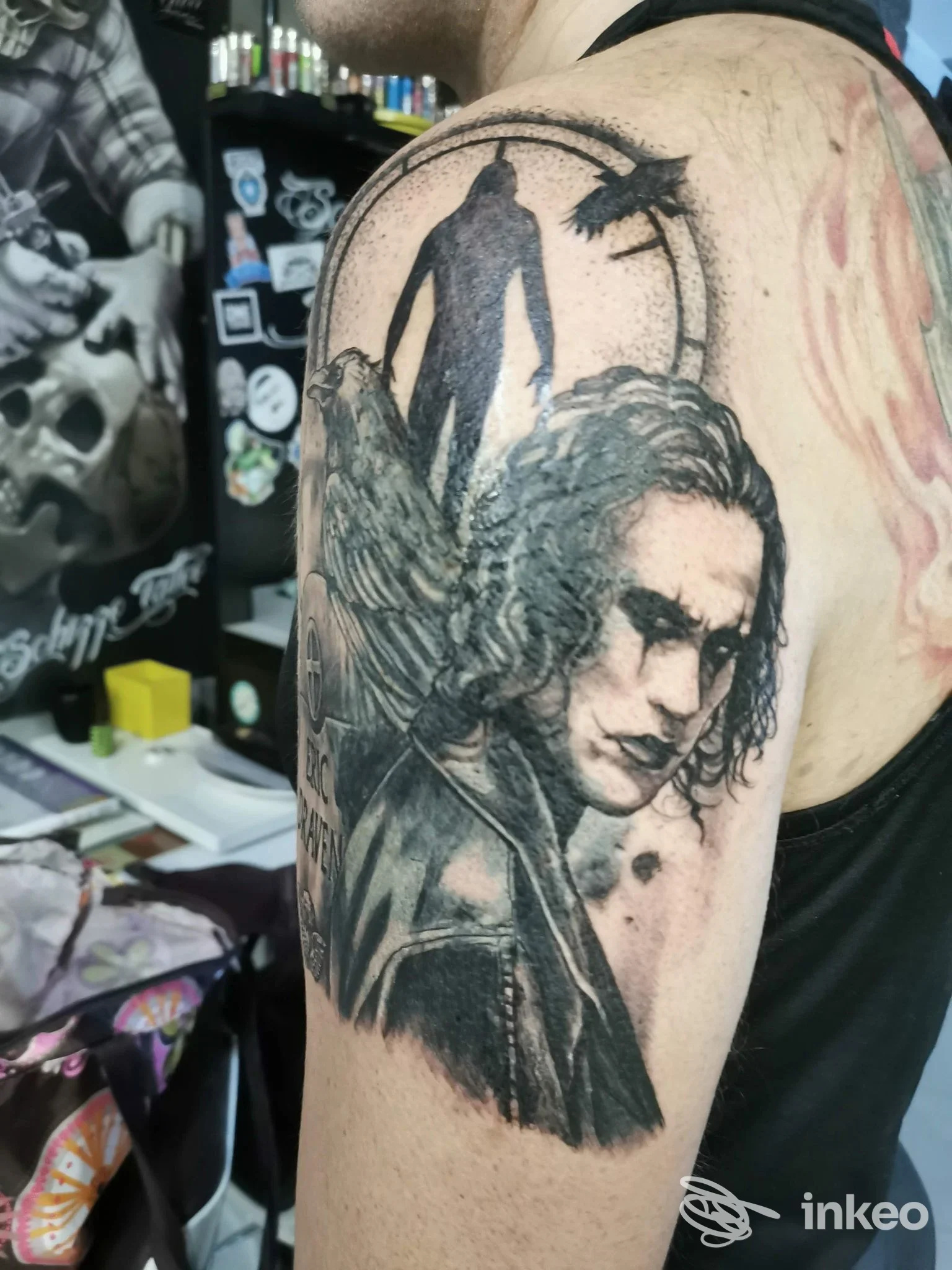 Tatuaggio realistico in bianco e nero sul braccio superiore, ritratto con ali e figura scura, foto scattata presso Schizzo Tattoo a Torino.