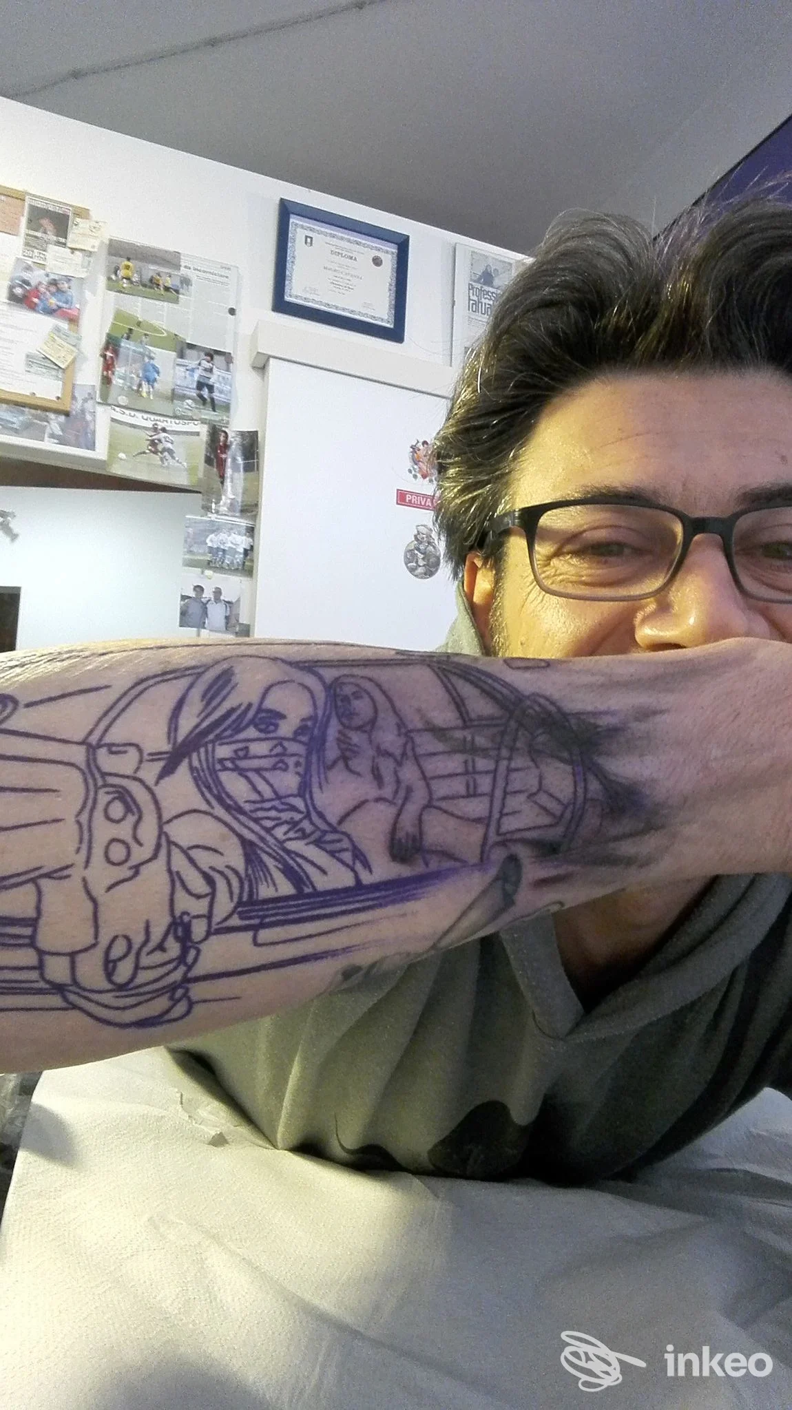 Primo piano dell'avambraccio tatuato con linee preparatorie; persona con occhiali nello studio Tattoo Communication, Acqui Terme.