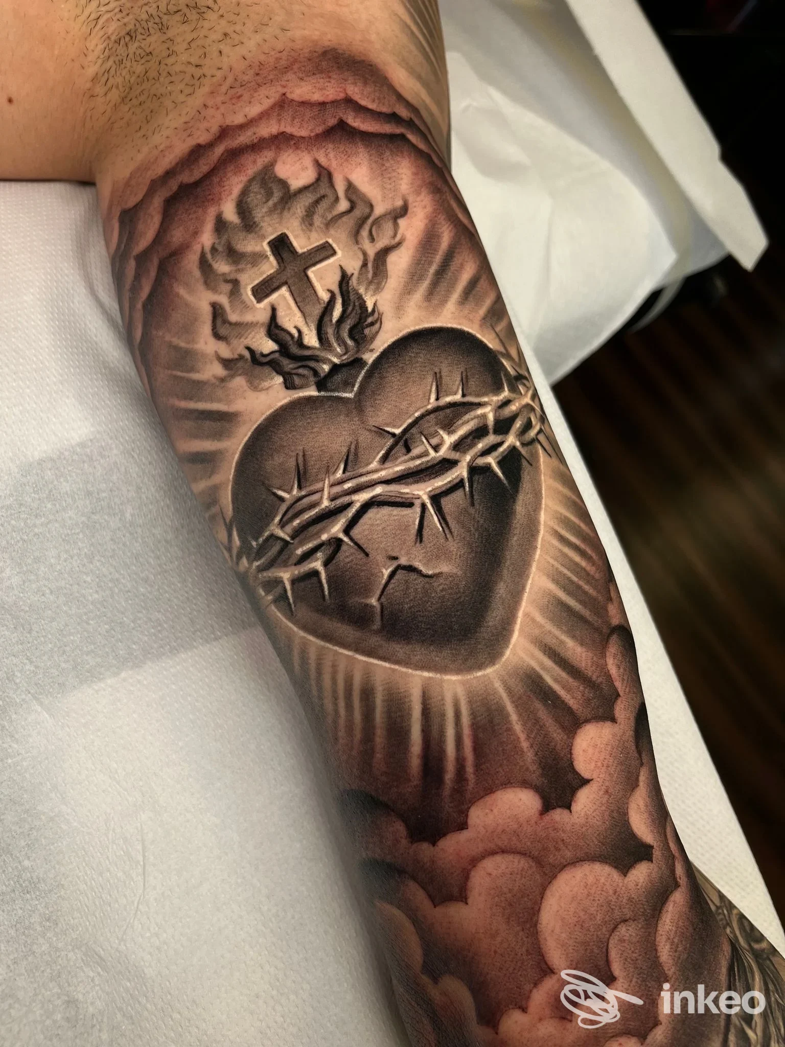Tatuaggio dettagliato del Sacro Cuore con fiamme, corona di spine e croce sull'avambraccio, realizzato da Tattoo & Piercing Torino - DOUBLE TRUCKS studio, Torino.