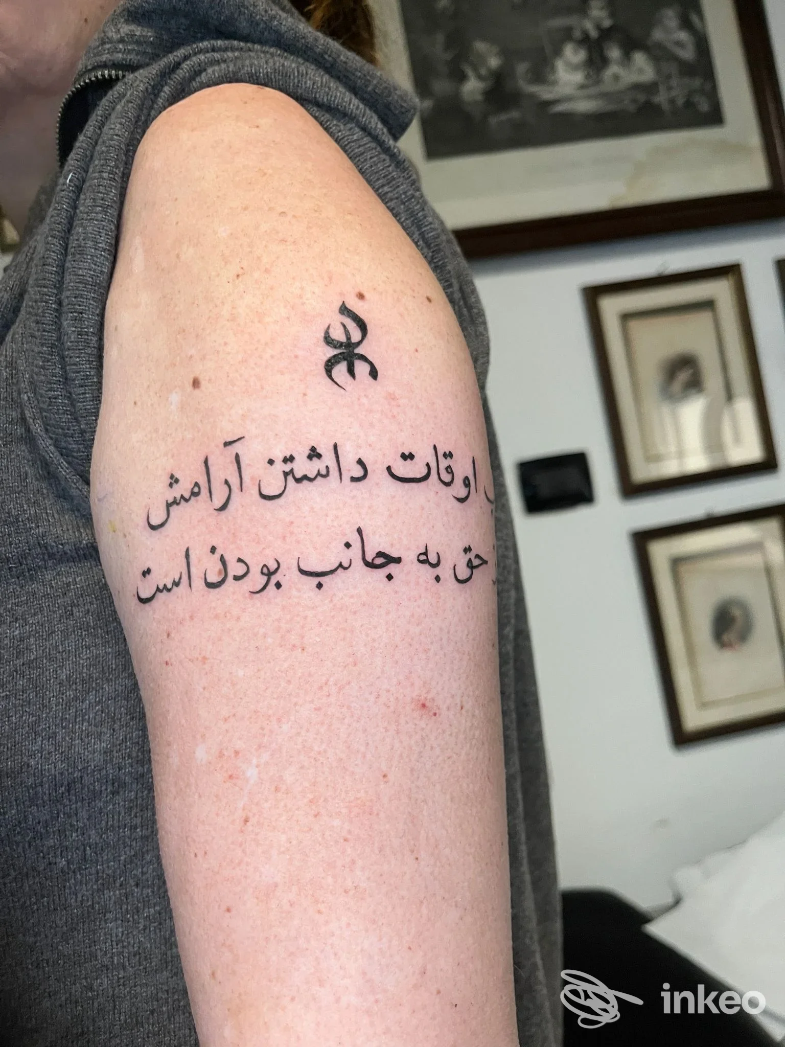 Tatuaggio testuale in persiano e piccolo simbolo sul braccio superiore, immagine dal portfolio di Tiga Tattoo Studio, Torino.