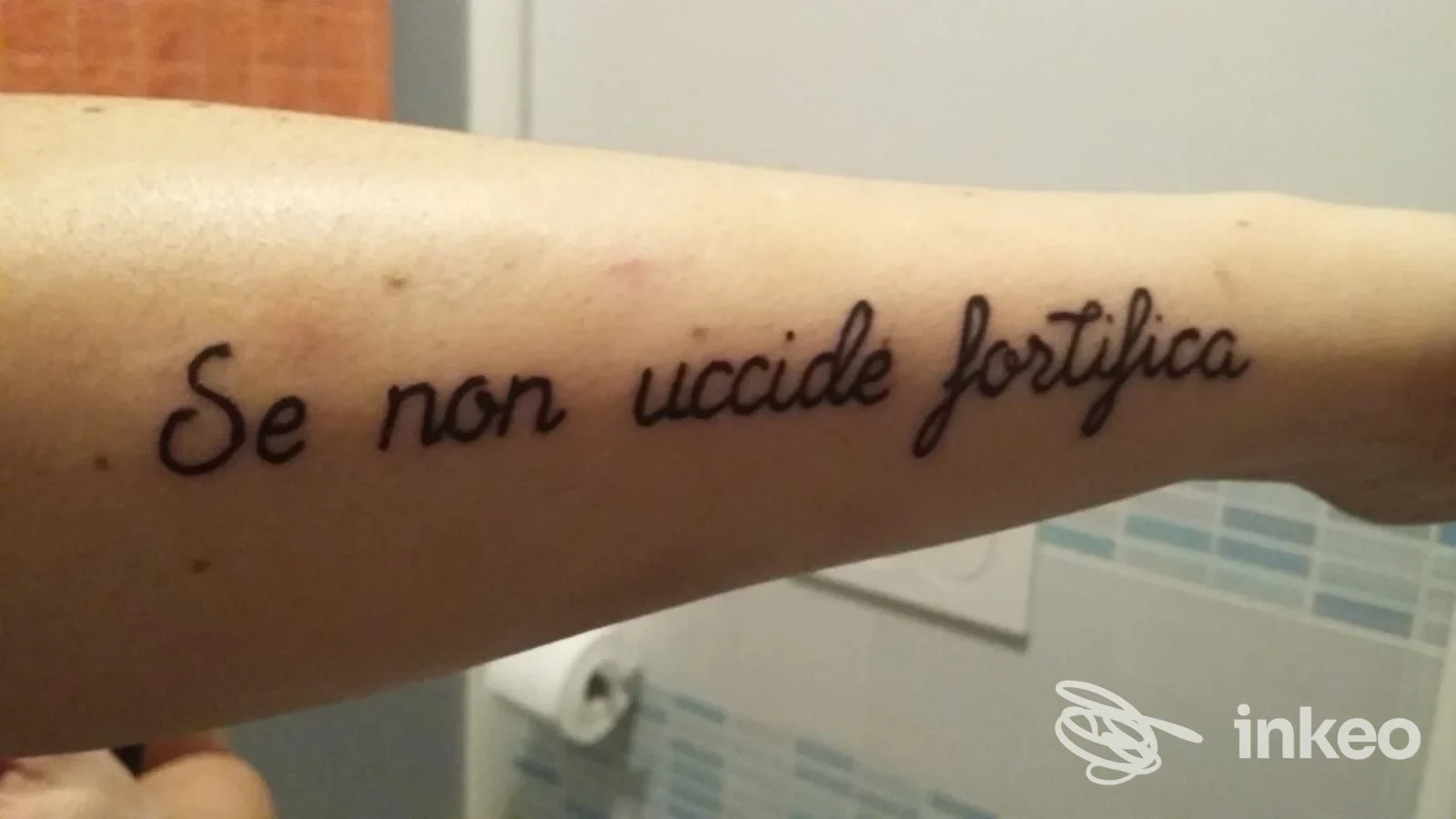 Tatuaggio testuale in inchiostro nero sull'avambraccio interno: 'Se non uccide fortifica'. Foto fornita da Tattoodrome, Borgo San Dalmazzo.