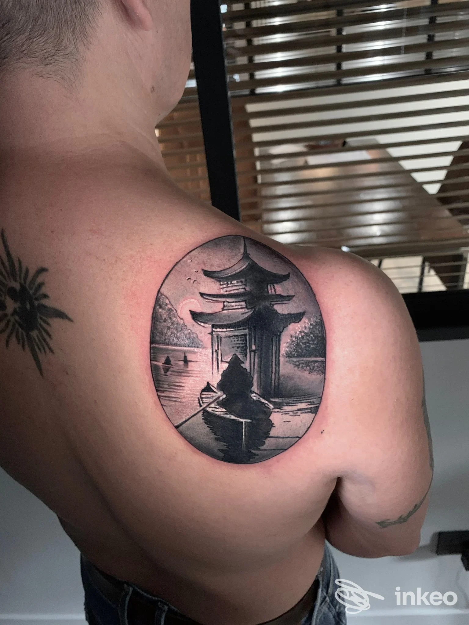 Tatuaggio in bianco e nero con pagoda e barca sulla spalla di un cliente, Taxi Tattoo Store Torino, Torino.