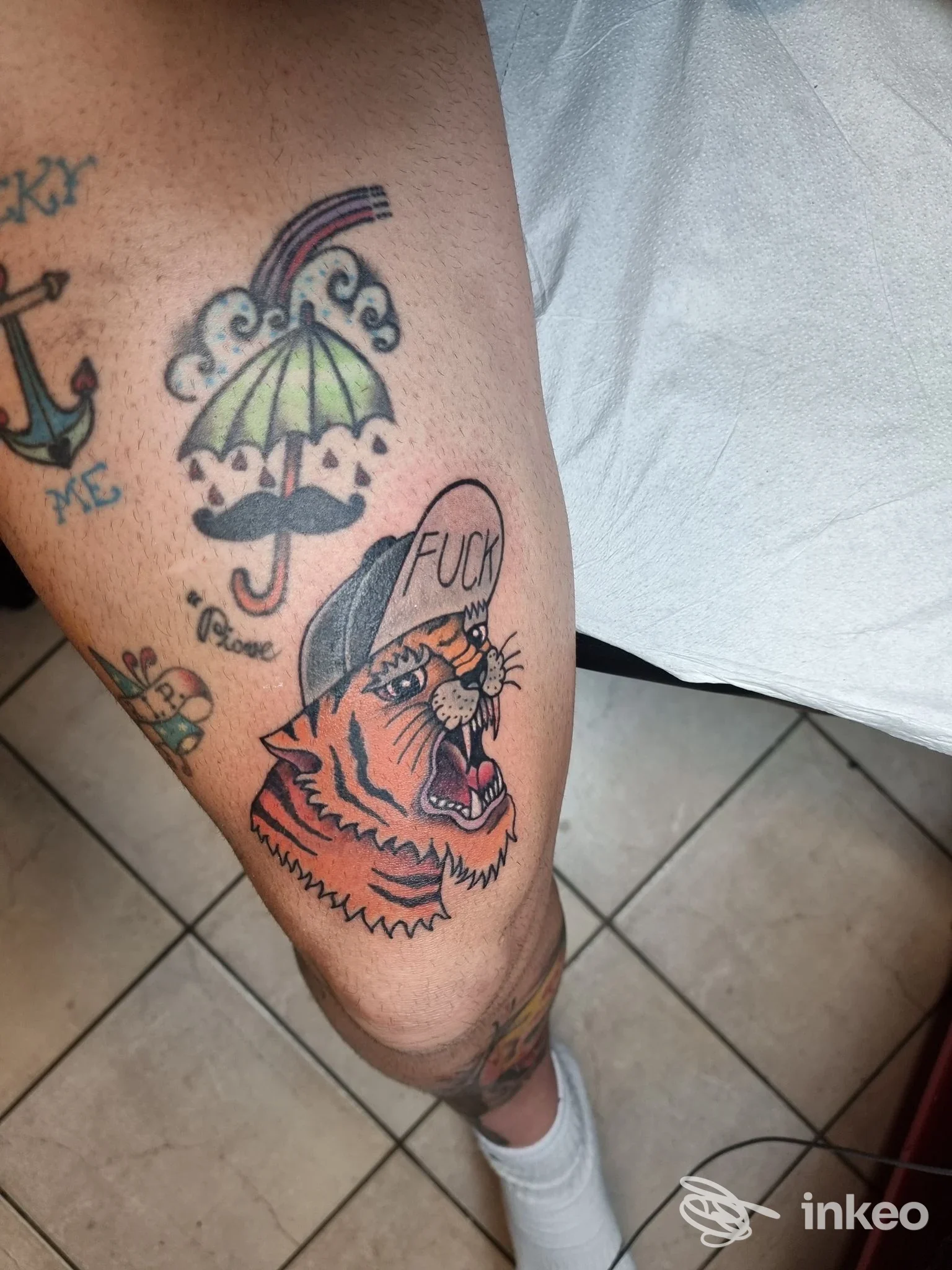 Tatuaggio di una tigre stilizzata con cappello sulla gamba, espressione feroce e colori vividi, realizzato da Sin & Salvation a Dello.