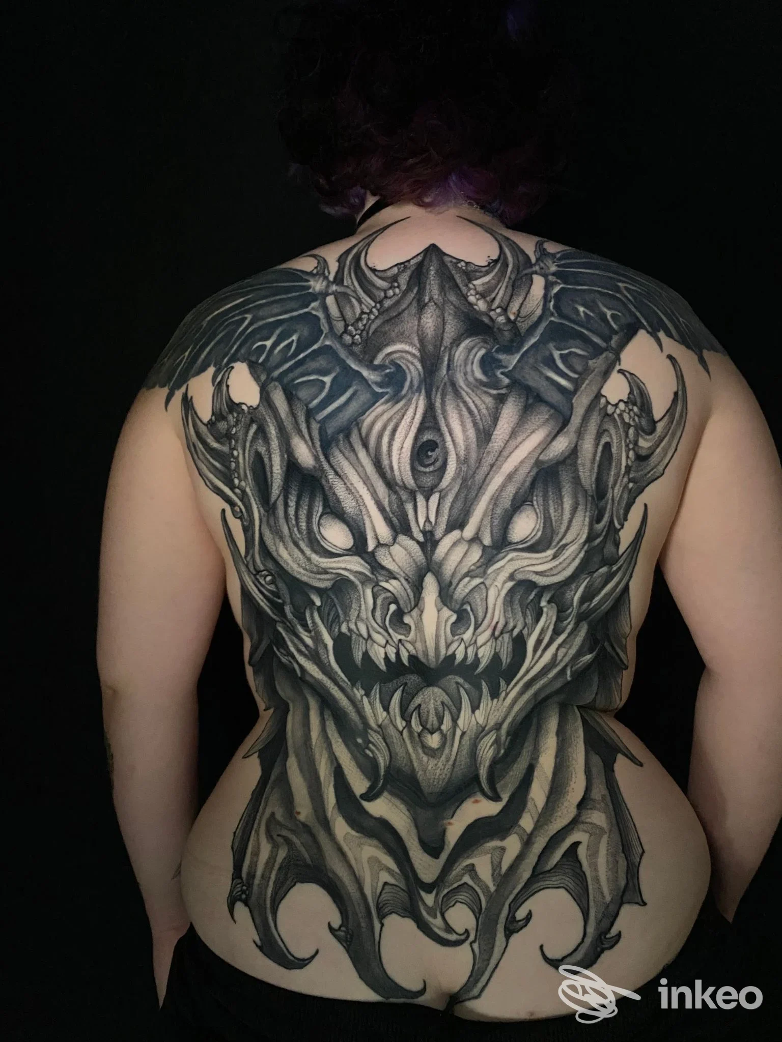 Tattoo esteso sulla schiena di una persona, con disegno scuro dettagliato che copre ampia area dorsale; nessun volto visibile, nessun testo o overlay visibile.