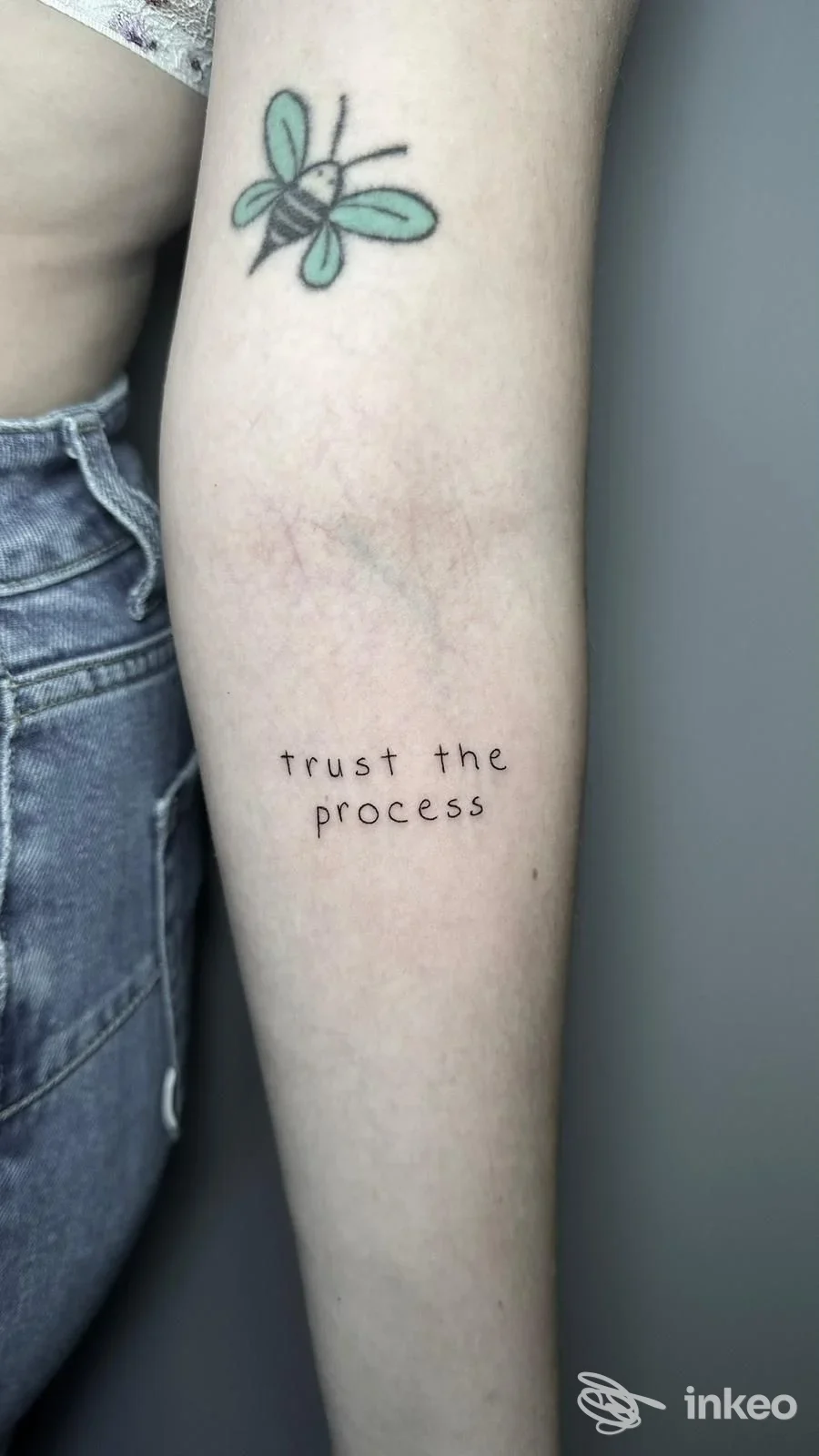 Tatuaggio sul braccio: farfalla colorata e la scritta "trust the process" sotto, su pelle chiara, senza altri elementi visivi, nello stile di Minas Morgul tattoo & art studio.