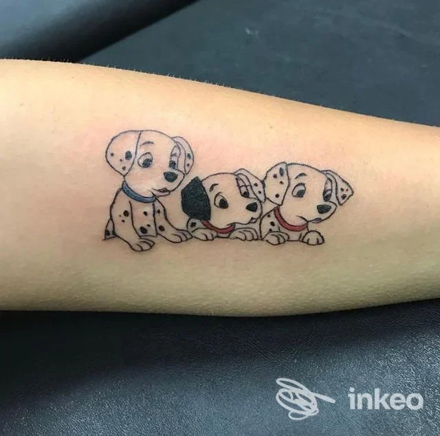 Tatuaggio sull'avambraccio raffigurante tre cuccioli di dalmata in stile cartone, linee sottili e piccoli tocchi di colore. SKIN DEEP tattoo studio, Putignano.