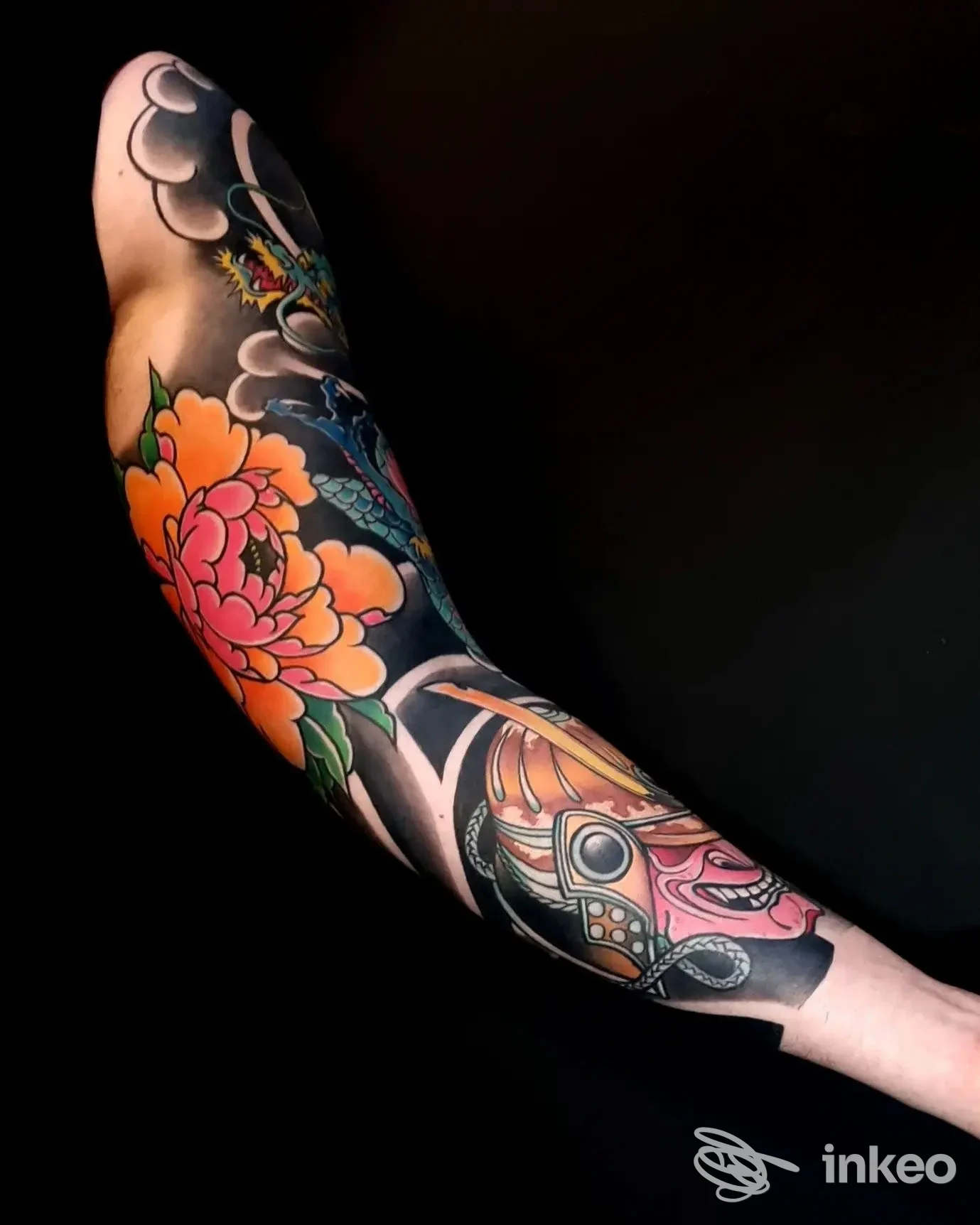 Manica tatuata a colori su braccio con grande fiore e maschera ornamentale, foto dallo studio Sacred Tattoo Bari (Bari).