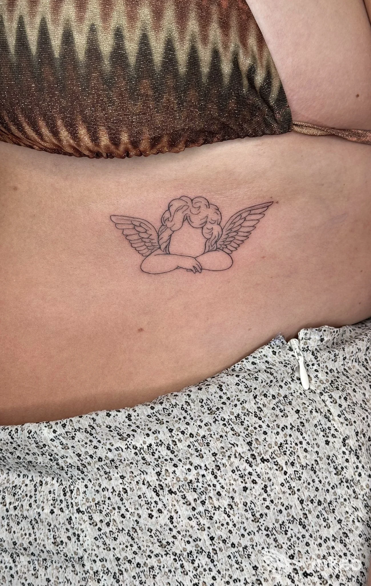 Tatuaggio linework di un piccolo angelo con ali sul fianco/torace sotto il seno, realizzato da Sanctum Tattoo Studio Gallipoli (Gallipoli).