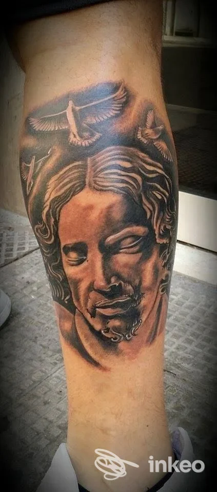 Tatuaggio realistico in bianco e nero sul polpaccio, volto e colombe — Skin Project Tattoo Studio, Bari.