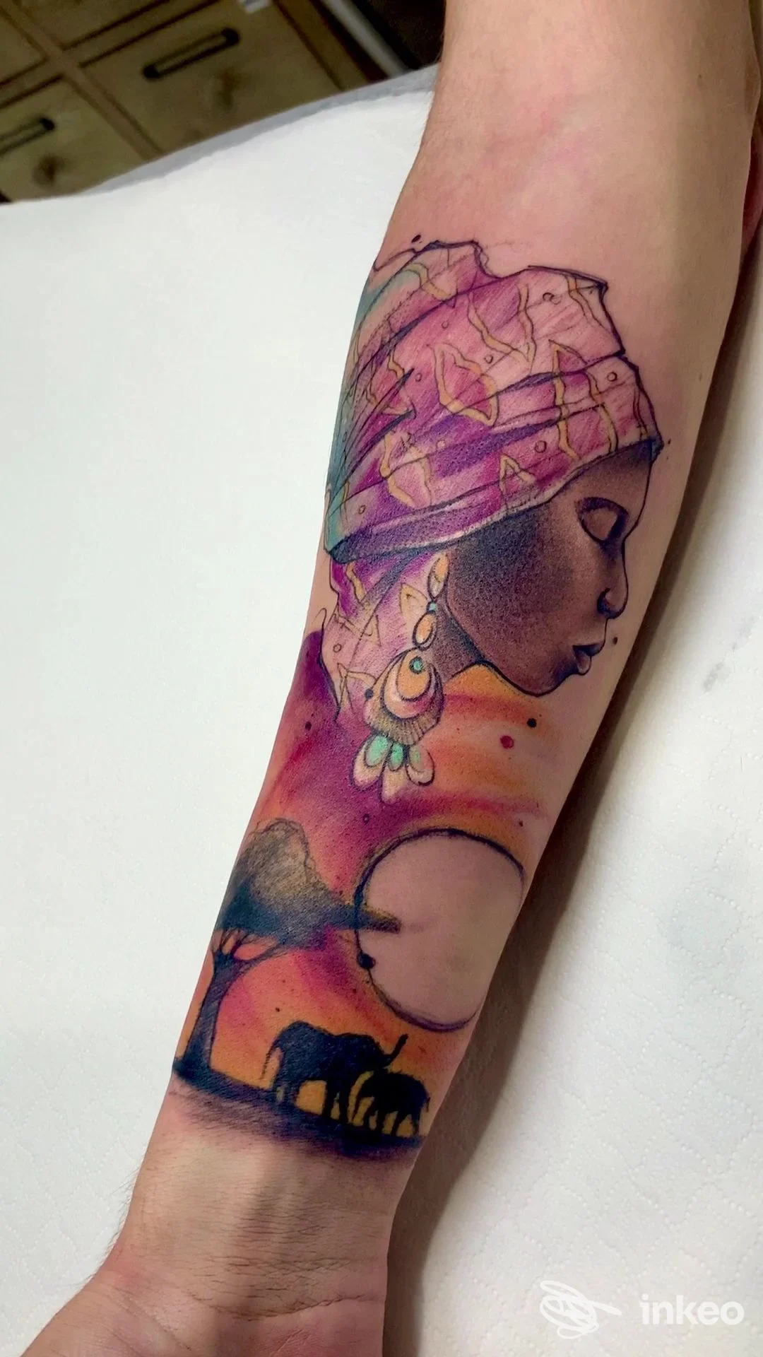 Tatuaggio a colori su avambraccio con profilo femminile e scena di elefanti, Smoun Tattoo, Mola di Bari.