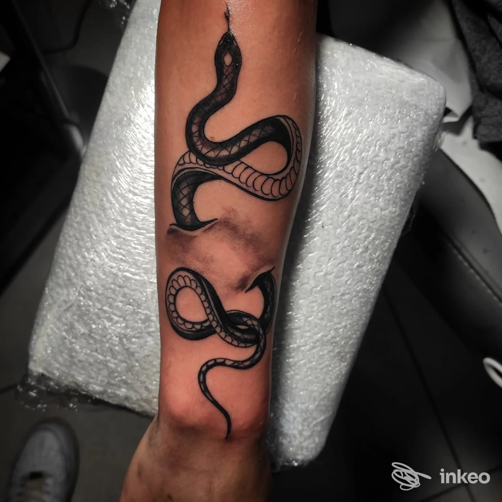 Tatuaggio di due serpenti neri lungo l'avambraccio, foto inviata da Squiggle Tattoo Studio a Capurso.