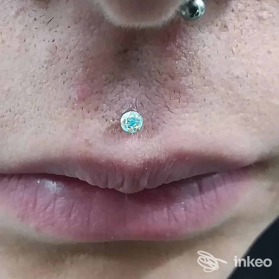 Primo piano di un piercing al filtro (philtrum) con gioiello a pietra, immagine fornita da Studio Piercing Polacca, Taranto.
