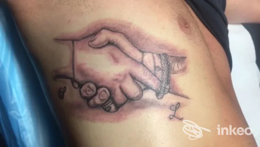 Tatuaggio sul fianco raffigurante due mani che si stringono, eseguito presso Studio25 tattoo&piercing a Pulsano.
