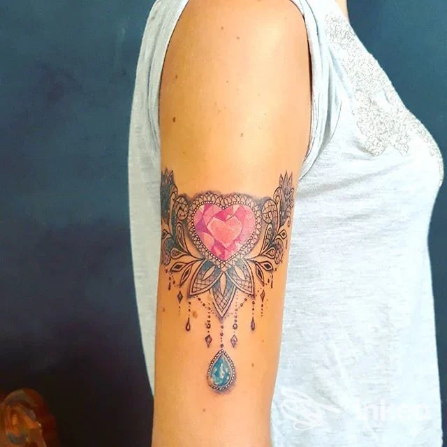 Tatuaggio colorato a forma di cuore con dettagli ornamentali sulla parte superiore del braccio, foto fornita da Sublime Tattoo a Taurisano.