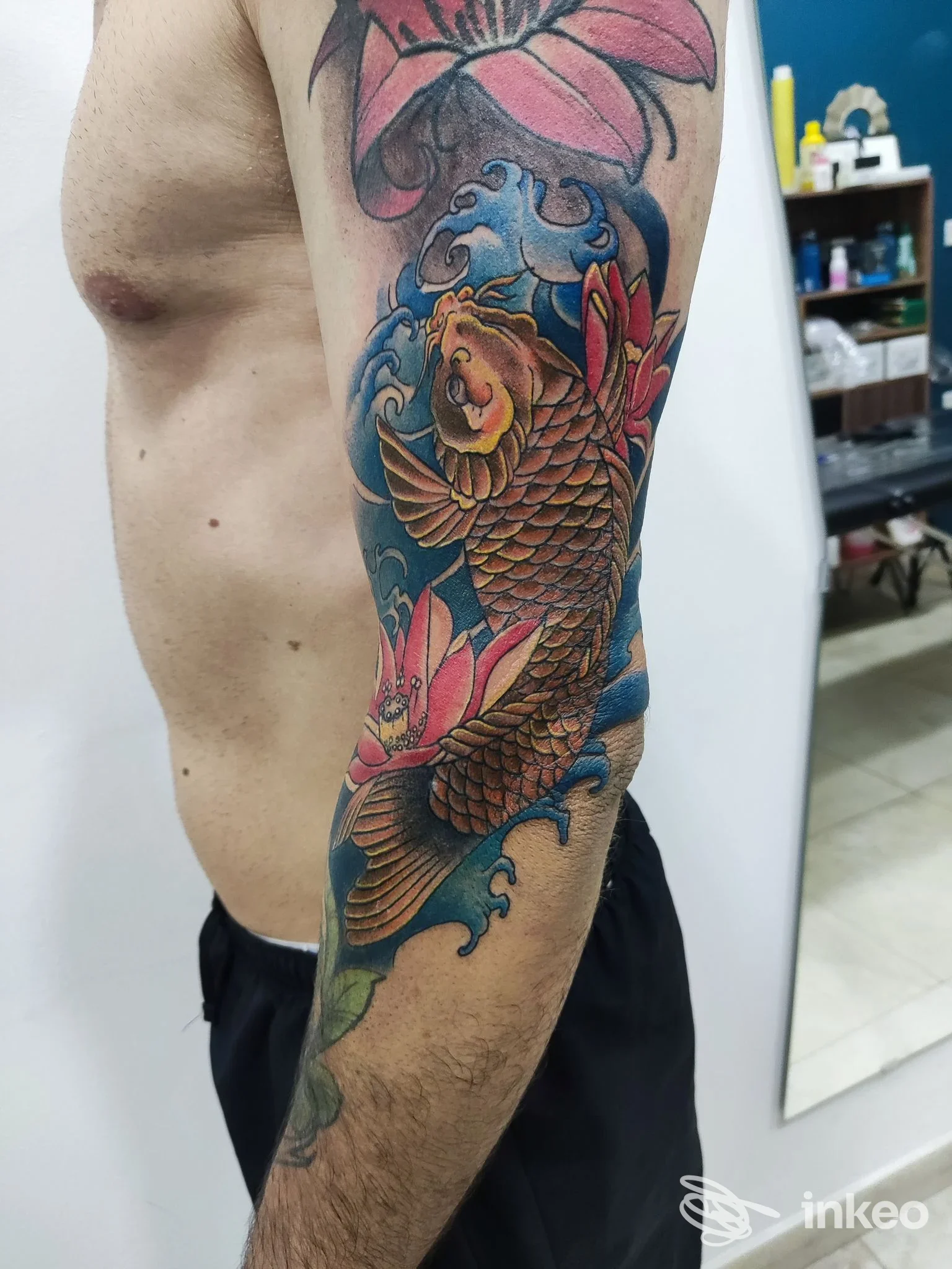 Grande tatuaggio di carpa koi colorata sull'avambraccio e braccio di un cliente, scattato nello studio Time Of Tattoo a Taviano.