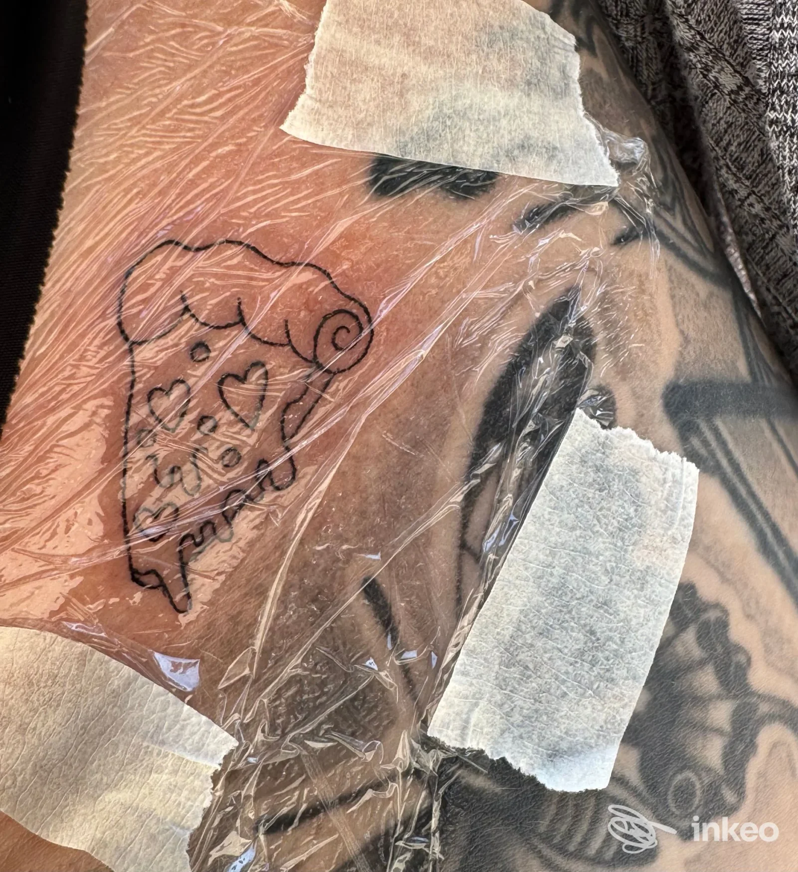 Tatuaggio fresco a forma di fetta di pizza con cuori su pelle, coperto da pellicola e nastro, Wild Cat Tattoo Studio, Bari.