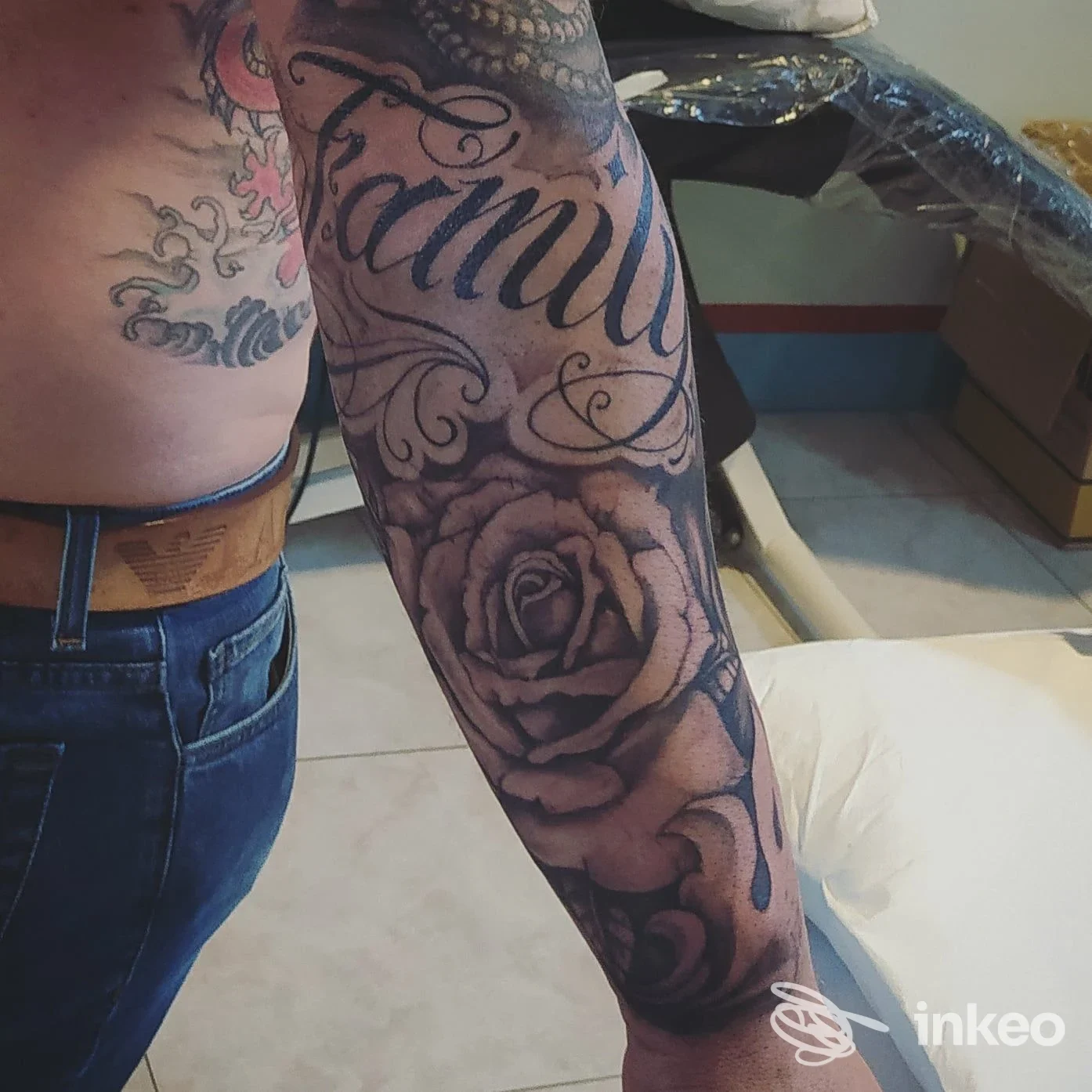 Manica tatuata con scritta "Family" e rose in bianco e nero, foto fornita da Xois Tattoo Studio, Manduria.