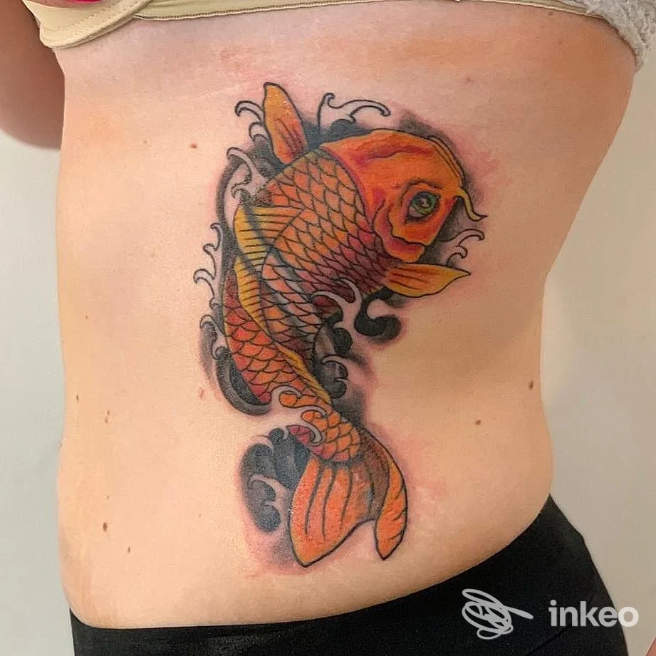 Grande tatuaggio di carpa koi arancione sul fianco destro, dettagli neri e sfumature, lavoro di body and soul tattoo ad Alezio.