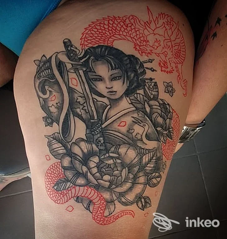 Tatuaggio su coscia raffigurante una figura femminile e un drago in nero e rosso, Body and Soul Tattoo, Alezio.