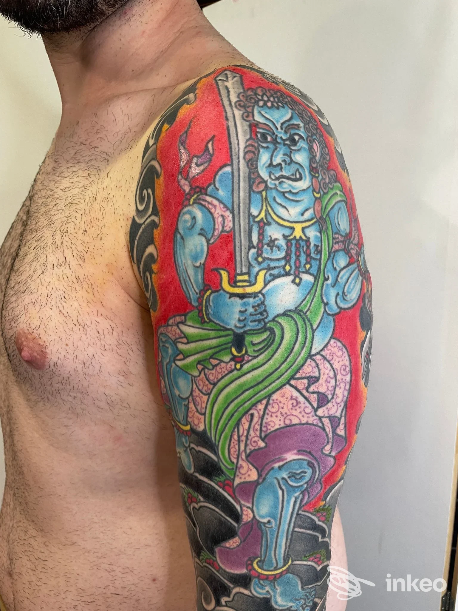 Tatuaggio a mezza manica su spalla e braccio superiore con figura stilizzata in colori vivaci, foto per Antipop Tattoo, Foggia.