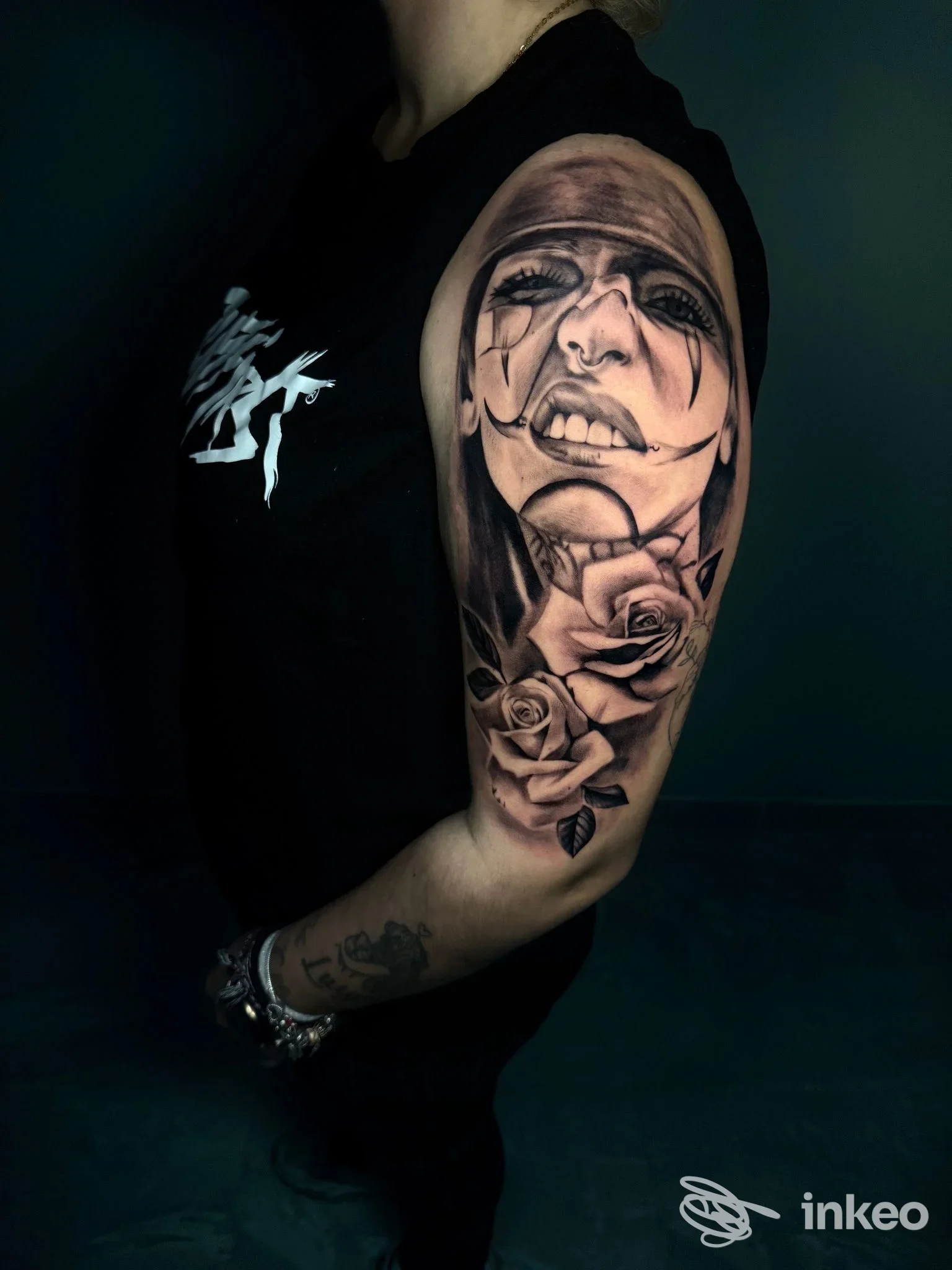 Tatuaggio realistico in bianco e nero con volto e rose sul braccio, foto fornita da Arosa Tattoo Studio, Tricase.